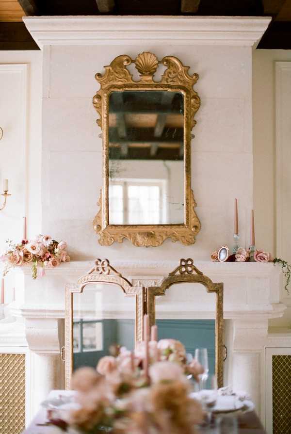 gold gilt mirror hangs above fireplace