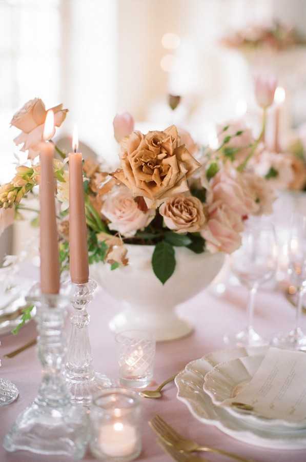 pink lit candles and pink and coffee coloured floral arrangement on wedding table