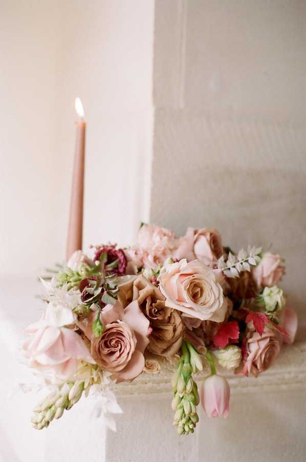 pink, coffee and burgundy coloured bouquet next to pink lit candle