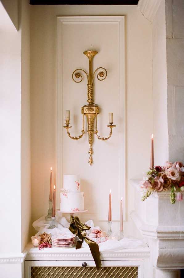 golden sconce above white and pink wedding cake