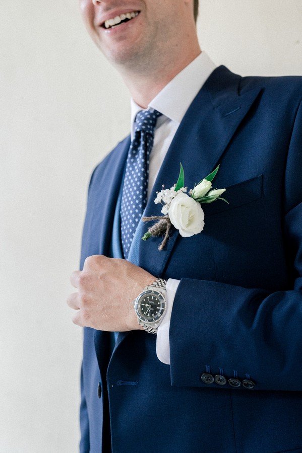 Closeup of groom's cream flower boutonnière on blue suit