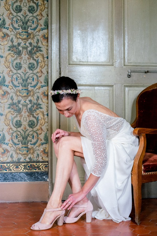 Seated bride fastens her shoe