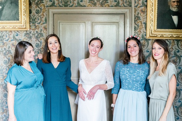 Bride in between her four bridesmaids all wearing various shades of blue dresses