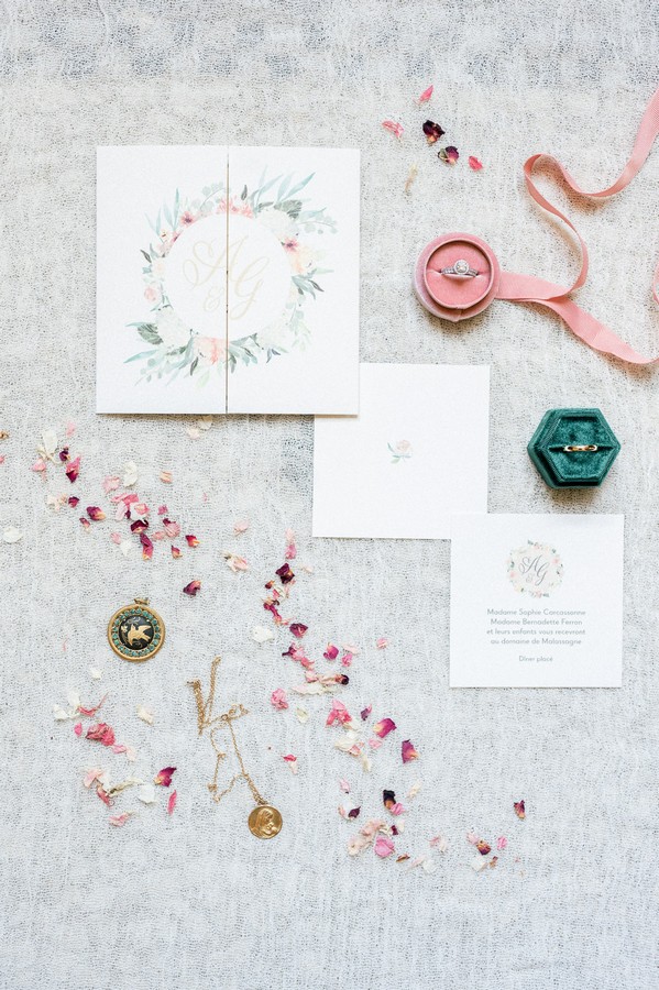 Bridal flat lay of petals, jewellery, ring boxes and floral stationery