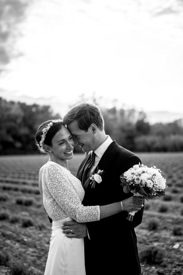 Black and white image of bride and groom in field in France