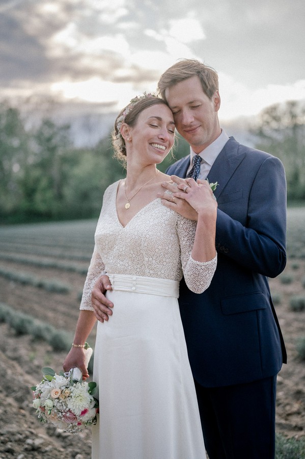 Groom holds his bride's waist in field in France