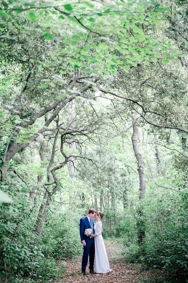 Bride and groom on garden path framed by green trees