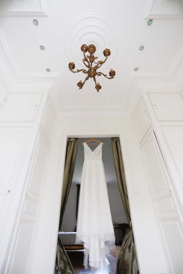 Brides dress hangs in doorway of white room