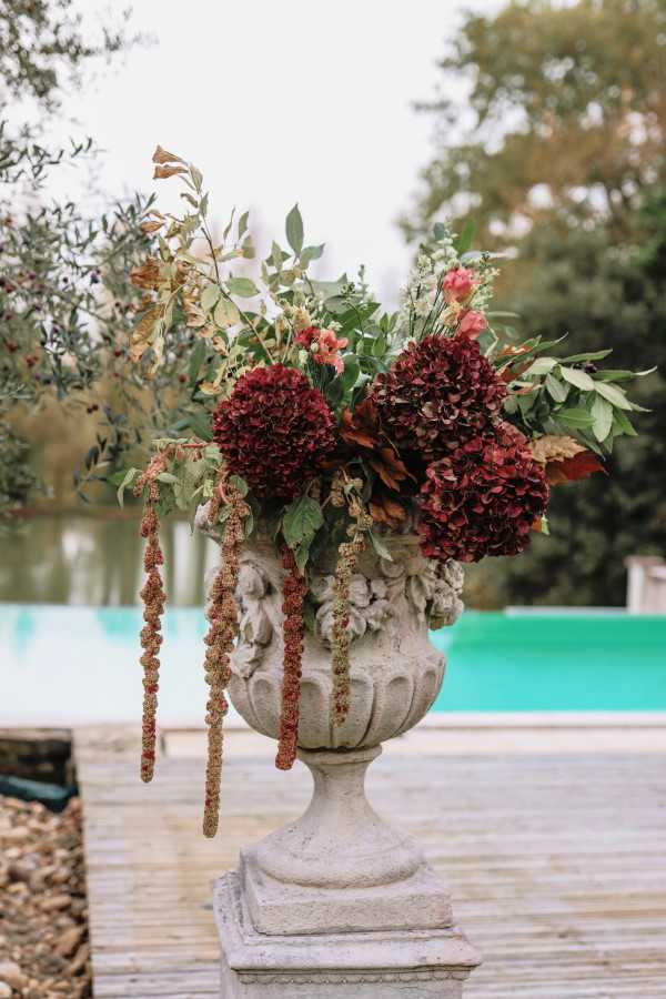 Burgundy, pink and eucalyptus floral arrangement in stone Medici vase