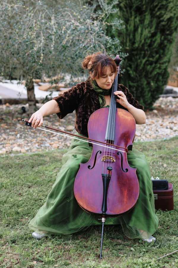 Cellist plays entrance music for bride wearing green skirt in garden of Chateau Lacanaud, Dordogne France