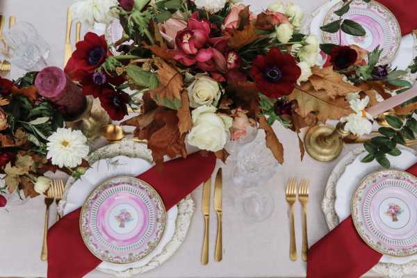 brides bouquet is laying on wedding table with burgundy flowers and table decorations and golden cutlery