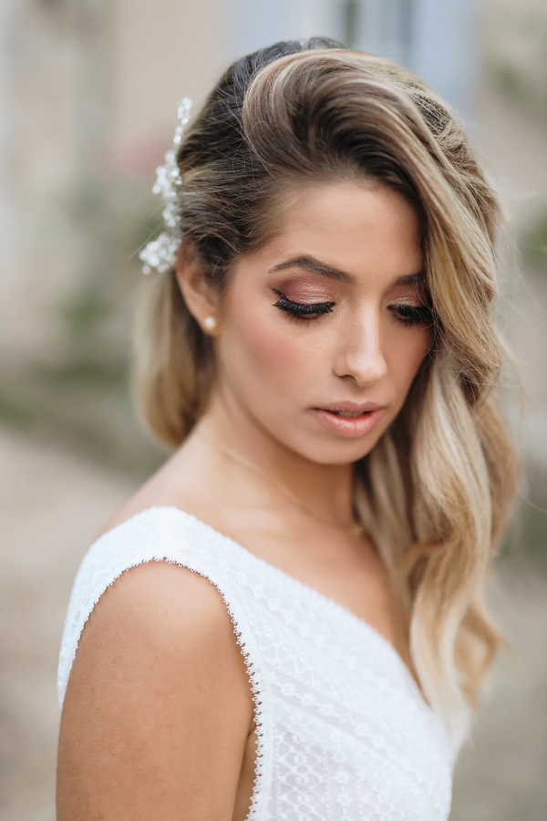 bride with side swept blonde hair and white pearl hair accessory pinned in