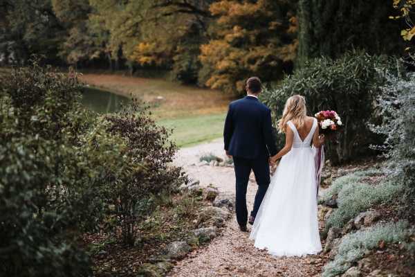 bride and groom descend garden steps of chateau lacanaud in france with back to camera