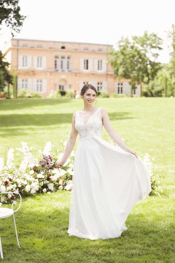 bride spins skirt on green lawn surrounded by flowers outside Chateau de Roquefoulet