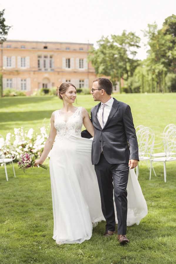 bride and groom arm in arm on the lawn of french chateau