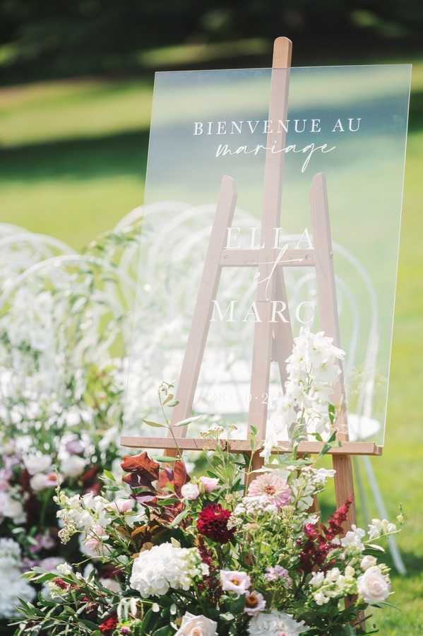 clear perspex wedding welcome sign on easel surrounded by flowers