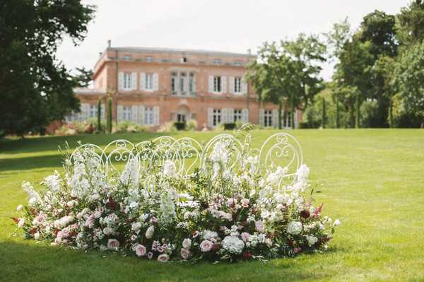 view of french chateau up grass hill behind floral arrangement and garden chairs