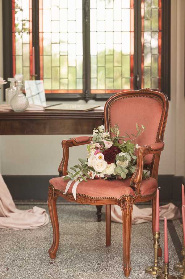 ornate maroon chair with bouquet on seat in front of bay window