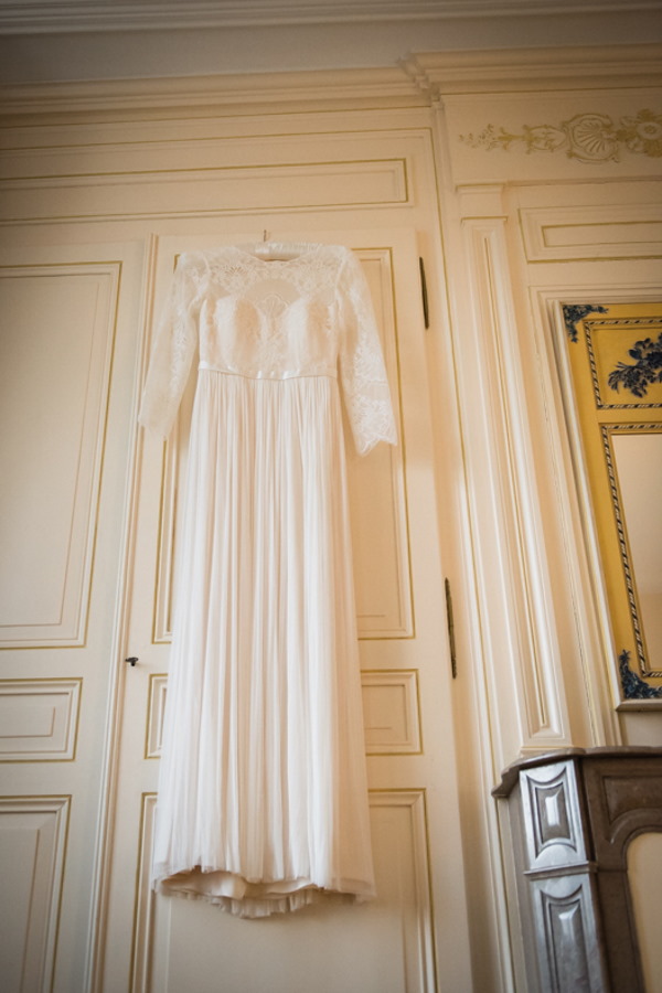 wedding dress hangs behind interior door of french chateau