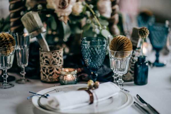 wedding wine glasses and tealight candles surrounded by green and cream foliage