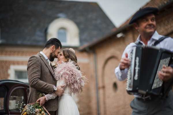 bride and groom share a kiss listening to an accordion player who is also in shot