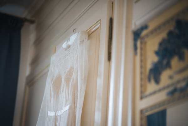 wedding dress hangs behind interior door of french chateau