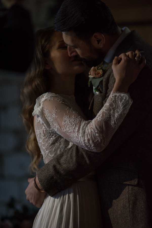 an almost silhouette of a bride and groom kissing in the dark