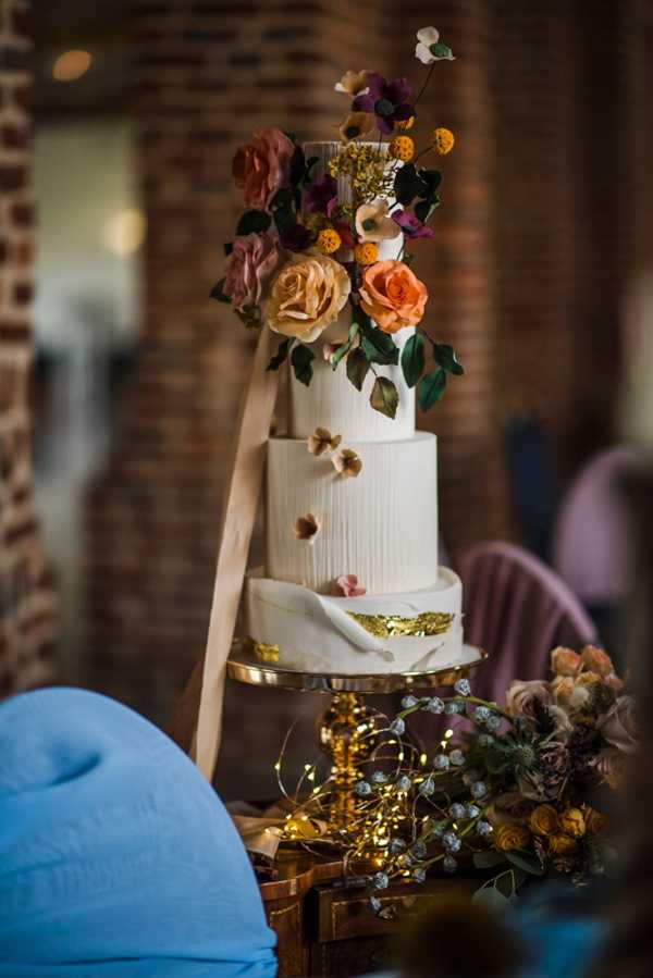 4 Tier rustic cream wedding cake decorated with fresh orange flowers