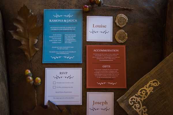 flat lay of red, green, cream and gold wedding stationery