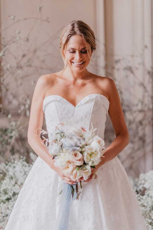 bride smiling at pastel bouquet in strapless wedding gown