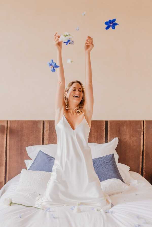 Bride on bed with arms in the air excited it is her wedding day