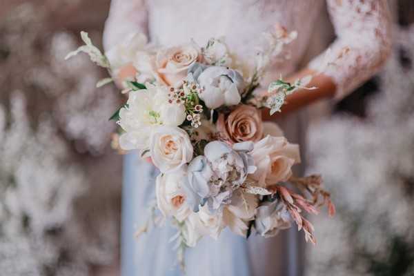 Pastel blue and pink bridal bouquet held by bride who fades into background