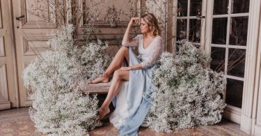 Bride in blue sitting amongs clouds of Baby's-breath flowers