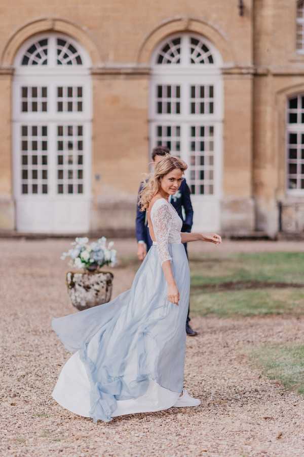 Bride's pale blue skirt trails behind her in the breeze as she walks toward her groom