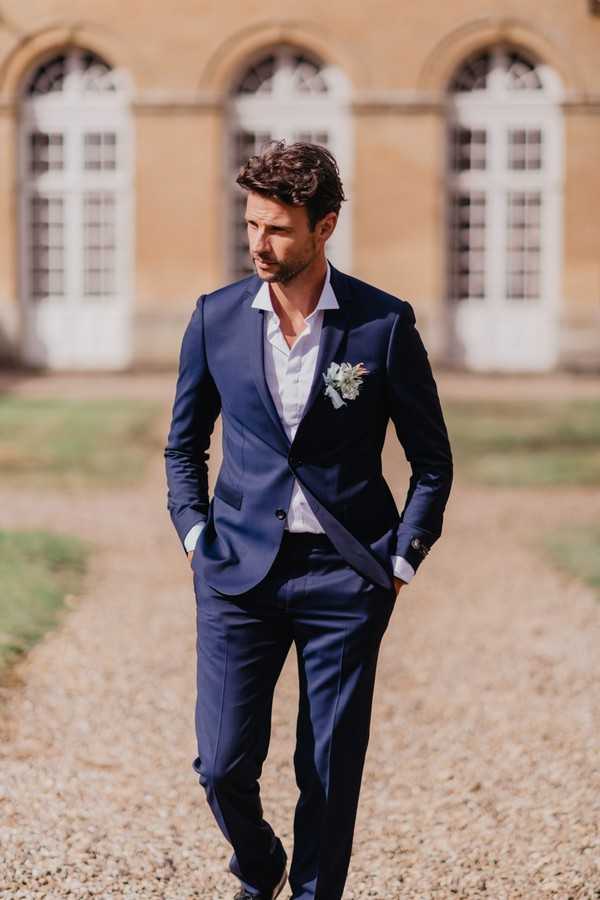 Groom in midnight blue suit with white buttonhole