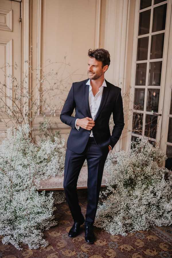 Groom surrounded by Baby's-breath flowers wearing blue suit