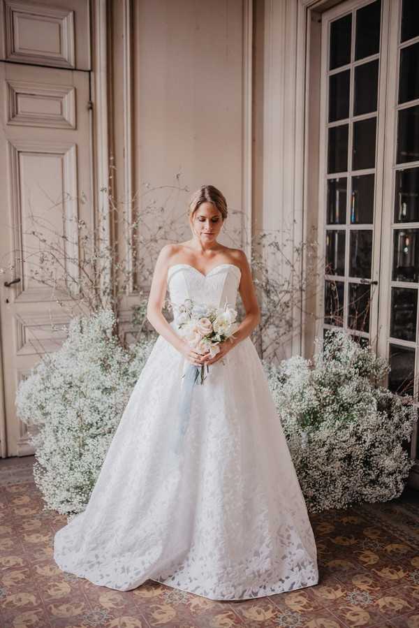 Bride surrounded by white Baby's-breath flowers in white strapless lace wedding gown