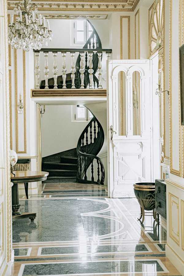 entrance hall of Chateau St George with black stone floors and white and gold trim doors and walls