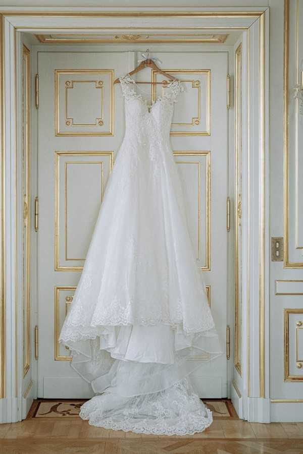 brides dress hangs from white and gold trim doorway