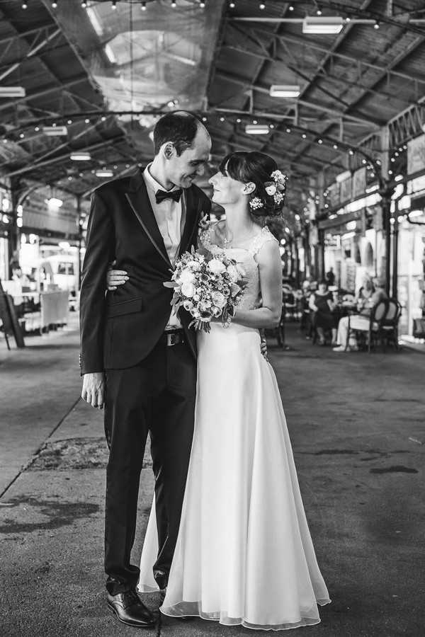 black and white image of bride and groom smiling at each other in industrial space with steel beams