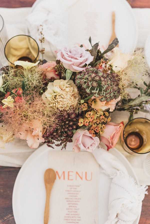 pink and cream wedding menu with small wooden spoon and pastel floral arrangement