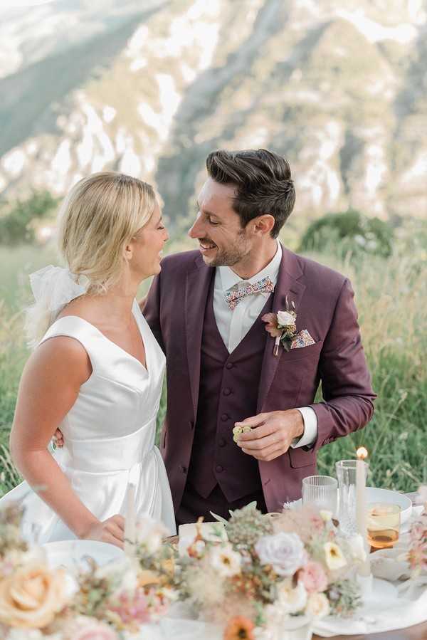 bride and groom smile at each other in a field for their spring picnic wedding