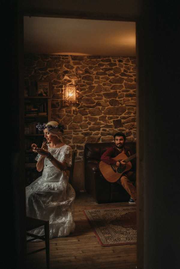 bride does makeup in handheld mirror and groom serenades her on his guitar