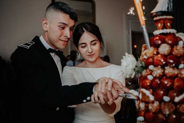 bride and groom cut their wedding cake (croquembouche)