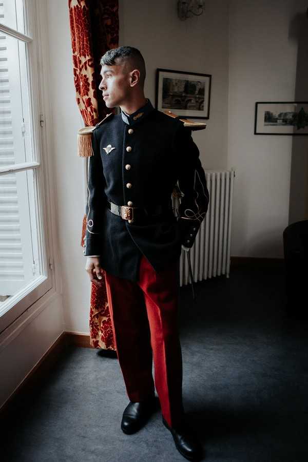 Groom in military uniform looks out french windows