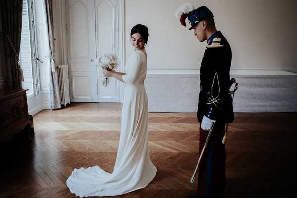 bride in retro dress and groom in full military uniform meet in french chateau