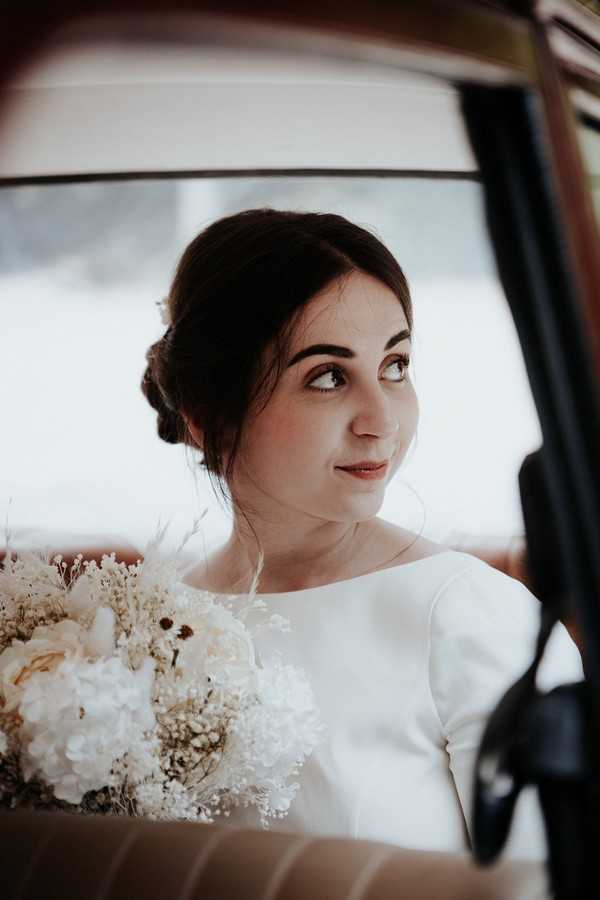 Bride looks out the window of a red vintage wedding car