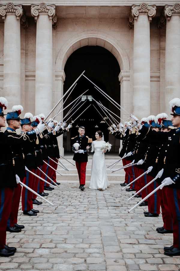 bride and groom walk out of the church through a saber arch