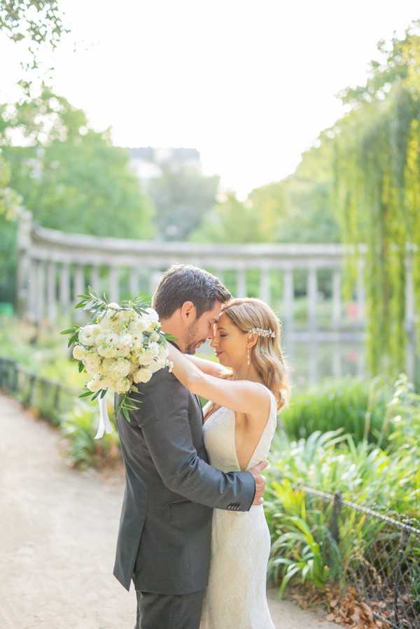 Bride and groom embrace surrounded by lush green gardens