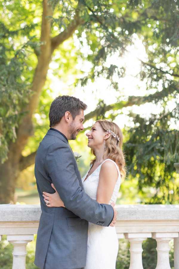 Bride and groom smile at the end of their romantic ceremony on stone bridge in Parc Monceau, Paris